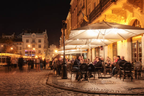 Lviv, Ukraine - April 19, 2019: Street cafe on the old streets of the night city. Lviv city in old town market square with illuminated night people  sitting at the tables in the cafe. long exposure stock photo