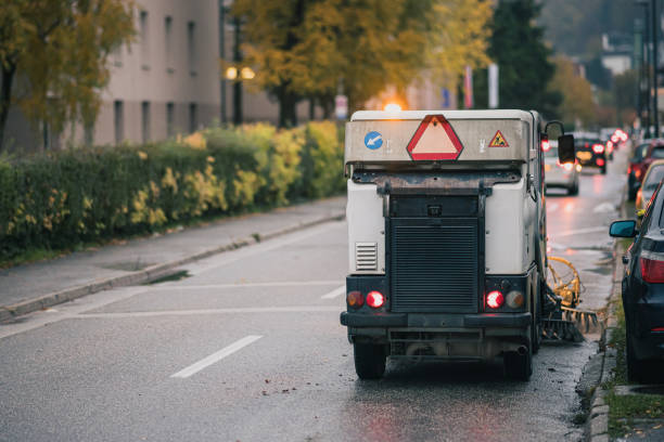 Street cleaner vehicle sweeping the roads in the city. Street sweeper machine making problems in the morning traffic. stock photo