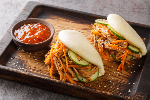 Street food bao sandwiches with pulled pork and vegetables close-up on a wooden tray. horizontal stock photo