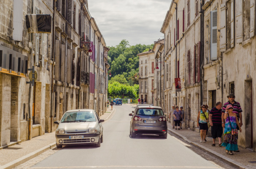 BrantA'me, France - August 8, 2013: Some cars pass by the main street of the village, and some tourists are by the sidewalk.