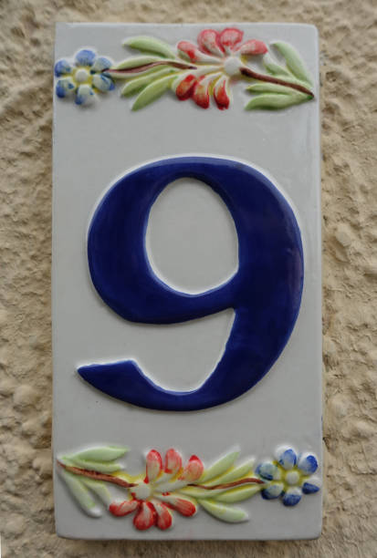 Street number on a ceramic with a floral decoration Entrance of a house stock photo