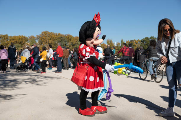 Street performer dressed as Minie Mouse, Spain Madrid, Spain - Nov 09, 2021: A street performer dressed as Minie Mouse, gives balloons to beg in the Retiro park images of minnie mouse stock pictures, royalty-free photos & images