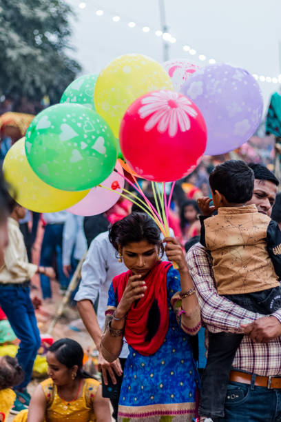 Street Vendor during the festival of Chhath GHAZIABAD, UTTAR PRADESH/INDIA - NOVEMBER 2019 : Girls selling Balloons during the CHHATH Puja celebration at the river Bank of Hindon, Ghaziabad chhath stock pictures, royalty-free photos & images