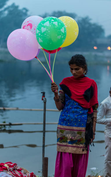 Street Vendor of balloon during Chhat Puja GHAZIABAD, UTTAR PRADESH/INDIA - NOVEMBER 2019 : Girls selling Balloons during the CHHATH Puja celebration at the river Bank of Hindon, Ghaziabad chhath stock pictures, royalty-free photos & images