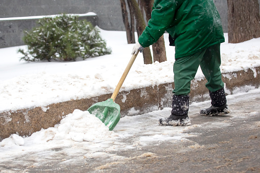 street worker shovels snow from the sidewalk