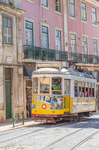 May, 2022. Lisbon, Portugal. A colorful tram full of tourists in a street of Lisbon.