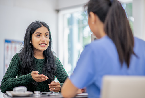 A young woman visits a specialist to consult, appearing optimistic in discussion.