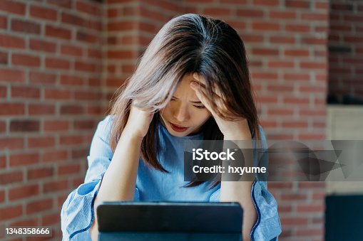 istock Stressed and tired young businesswoman using digital tablet 1348358666