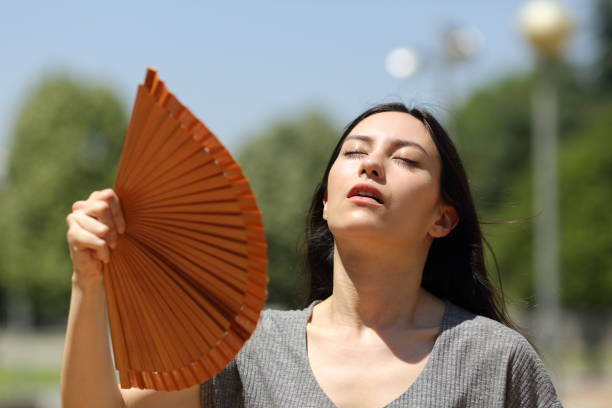 Stressed asian woman fanning suffering heatstroke stock photo