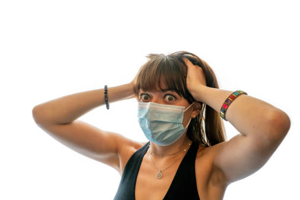 donna stressata che indossa una maschera medica per il viso, mani nei capelli - patrick zaki foto e immagini stock