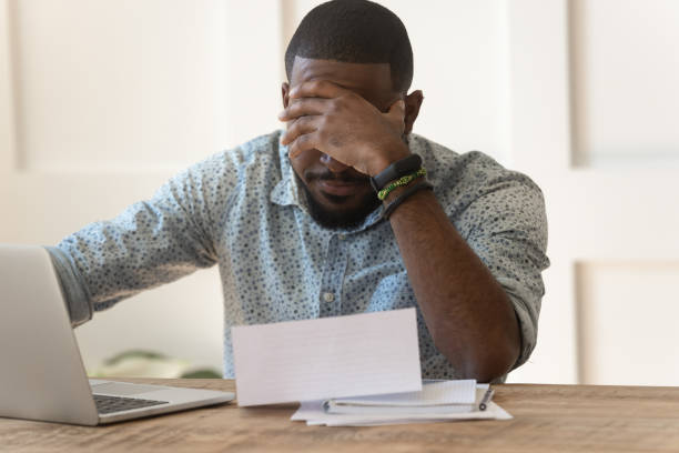 gestrest door afro-amerikaanse lezen slecht nieuws in brief. - geldstress stockfoto's en -beelden