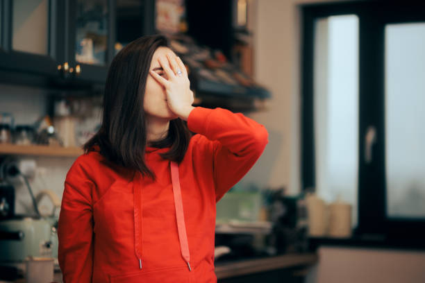 Stressed Woman Making Face Palm Gesture Standing in the Kitchen stock photo