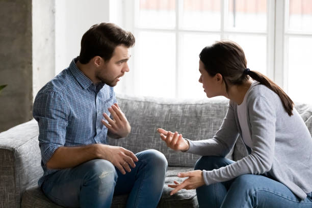 Stressed young married family couple arguing, blaming each other. Stressed young married family couple arguing emotionally, blaming lecturing each other, sitting on couch. Depressed husband quarreling with wife, having serious relations communication problems. arguing photos stock pictures, royalty-free photos & images