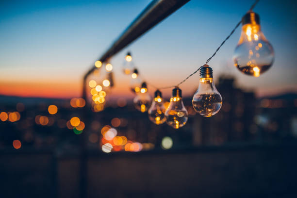 String light bulbs at sunset Close up picture of a string light bulbs at sunset on the rooftop. light natural phenomenon stock pictures, royalty-free photos & images