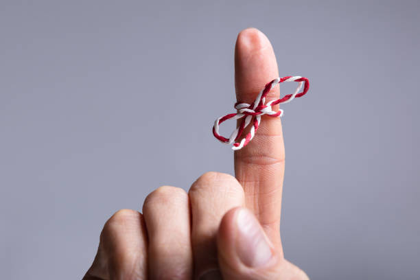 String On Person's Finger Close-up Of Person's Finger With Tied Ribbon Bow Over Gray Background reminder stock pictures, royalty-free photos & images