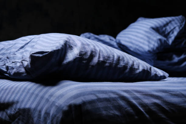 Striped grey bedding in unmade bed stock photo