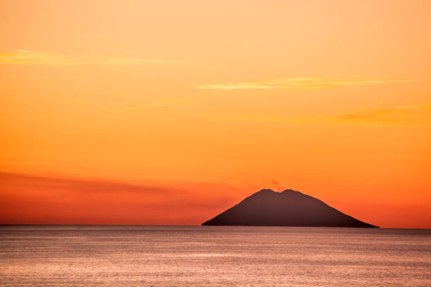 Stromboli active volcano against colorful sunset in Italy, view from Calabria coast. stock photo