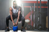 istock Strong adult black African men swing kettlebell to do gym exercise and weight lifting inside of fitness gym to workout for body strength and firm arms muscle and good physical body health. 1313069470