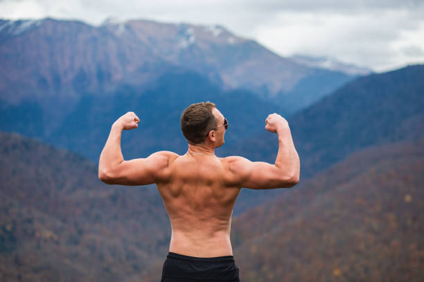 Strong male athlete looking at the mountain, rear view. Workout in the cold mountains stock photo