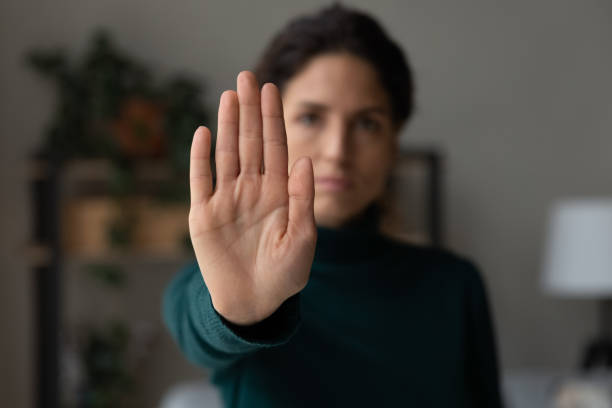 Strong young lady extending hand saying no to harassment abuse stock photo