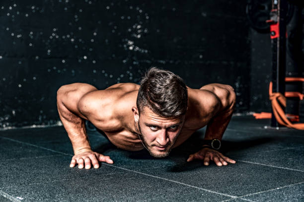 Strong young toned muscular fitness man push ups workout training on the gym floor stock photo