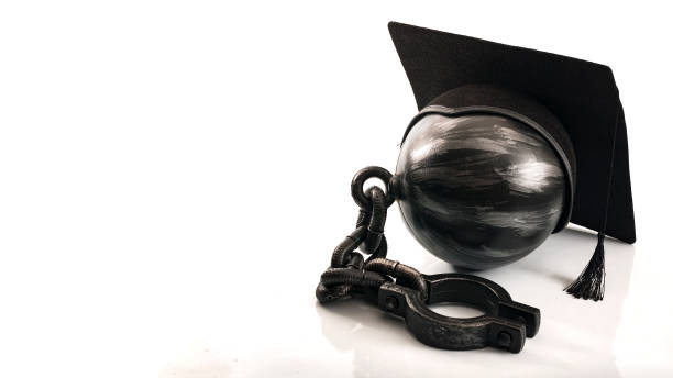 Student debt concept with ball and chain and copyspace Student debt concept with ball and chain wearing graduation cap symbolizing the burden tuition costs represent for students attending college or university on credit, with copy space isolated on white student debt stock pictures, royalty-free photos & images