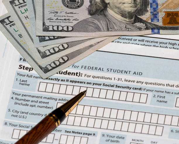 Student financial aid application forms for college tuition loans and grants with one-hundred dollar bills and ballpoint pen landscape, no people, student loan debt crisis student loan stock pictures, royalty-free photos & images
