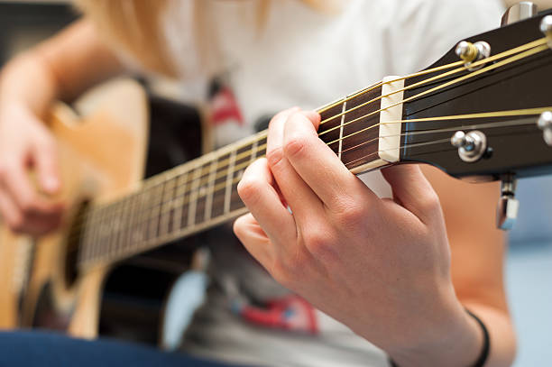 Student girl practicing the guitar close-up with focus on hand stock photo