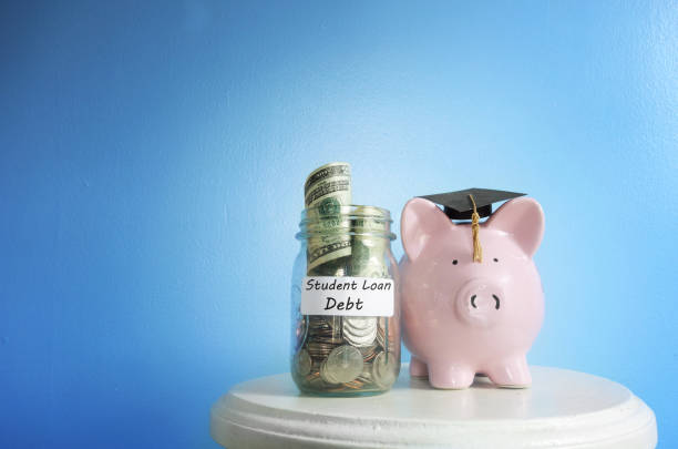 Student Loan debt Piggy bank with graduation cap beside a student loan coin jar student loan stock pictures, royalty-free photos & images