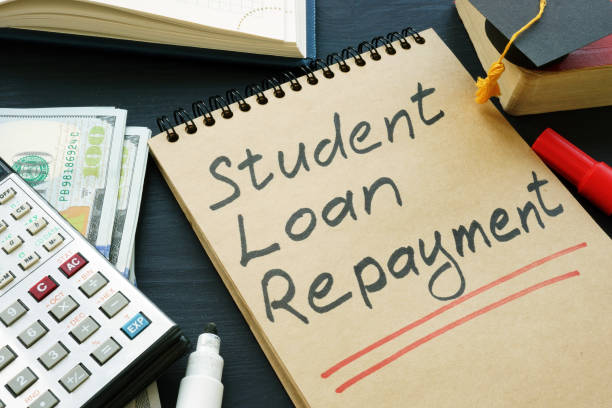Student loan repayment sign, notepads, calculator and cash. stock photo