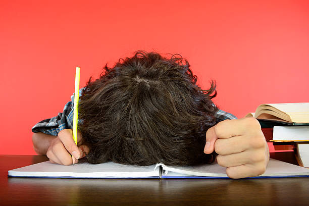 Student with Head on Notebook stock photo