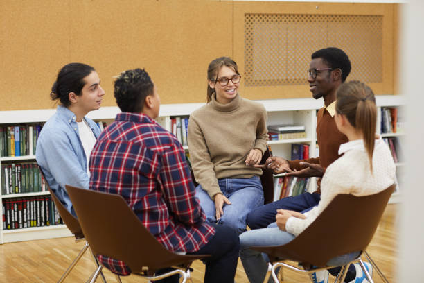 Students Enjoying Discussion Multi-ethnic group of young people sitting in circle and sharing ideas during class in college, copy space drug rehab stock pictures, royalty-free photos & images