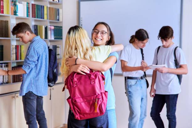 Students girls hugging at the meeting, group of teenagers in school library stock photo