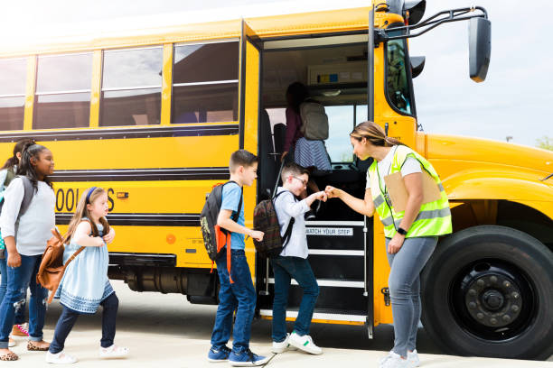 Students give fist bumps to bus driver Cheerful female school bus driver or teacher gives students fist bumps as they board a school bus. school bus driver stock pictures, royalty-free photos & images