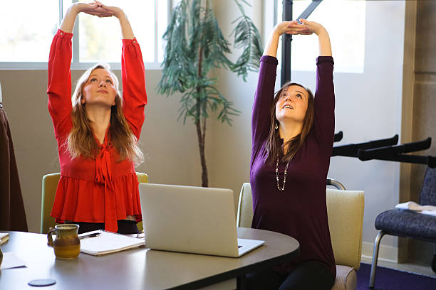 Students or Young Business Women Doing Yoga Stretching Working Studying group of young business people or students, discussing projects, working together, collaborating, and using technology, and doing yoga to take a break good posture stock pictures, royalty-free photos & images