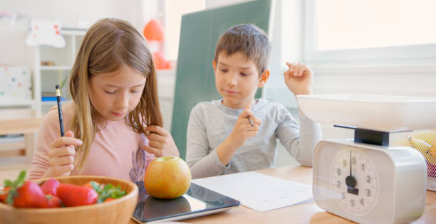 Students weighing apple in classroom stock photo
