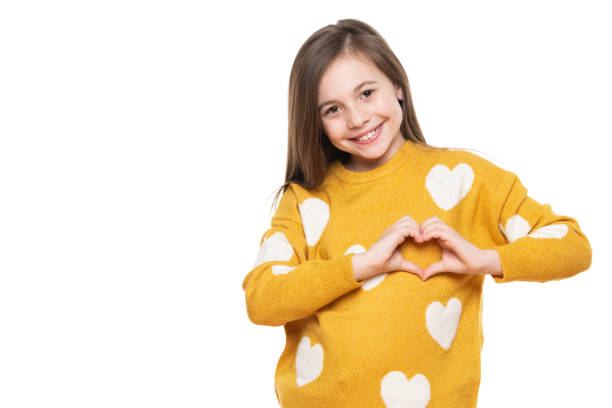 studio portrait of a little girl on white background making a heart gesture with her hands. fostering a child, humanitarian aid, cooperation, donation and support concept. - foster kids imagens e fotografias de stock