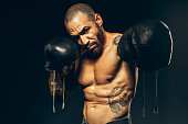 istock Studio portrait of a muscular boxer with a naked torso on a dark background. The Latin American puncher's attack 1333564017