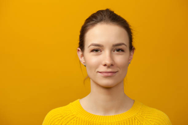 Studio portrait of an attractive 20 year old woman in a yellow sweater on a yellow background