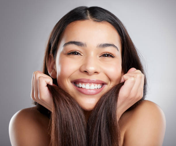 Studio portrait of an attractive young woman holding her hair against a grey background My hair grew so much! beautiful fresh skin stock pictures, royalty-free photos & images