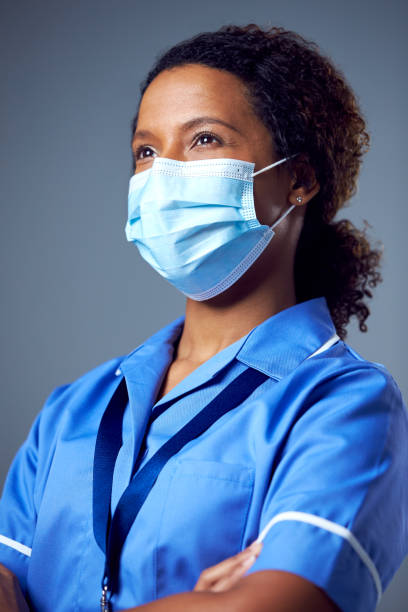 Studio Portrait Of Female Nurse Wearing Uniform And Face Mask stock photo