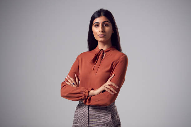 Studio Portrait Of Serious Young Businesswoman With Folded Arms Against Plain Background stock photo