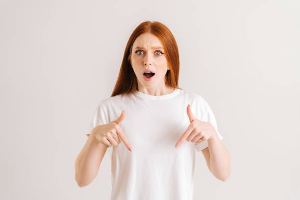 Studio portrait of shocked young woman open mouth recommending suggest select advert pointing index fingers down on isolated white background stock photo