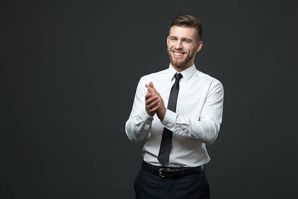 Studio portrait of young happy handsome businessman claping hands. stock photo