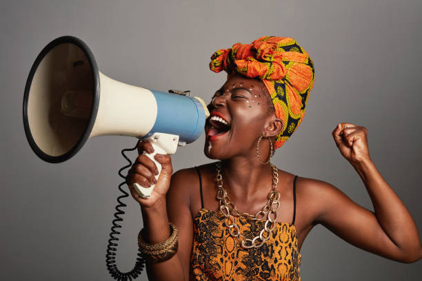 Studio shot of a beautiful young woman wearing traditional African attire and holding a megaphone stock photo