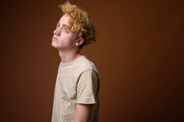 Studio shot of young man with curly blond hair wearing casual clothes against colored background Studio shot of young man with curly blond hair wearing casual clothes against colored background horizontal shot young redhead nude stock pictures, royalty-free photos & images