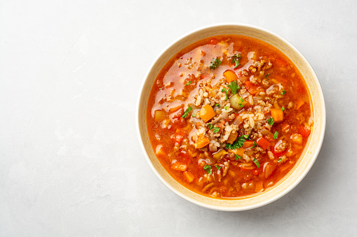 Stuffed pepper soup in bowl on concrete background. Top view, copy space.