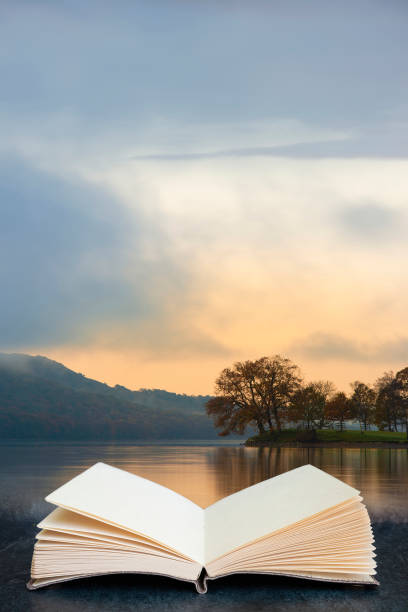 Stuning Autumn Fall sunrise landscape over Coniston Water with mist and wispy clouds coming out of pages in book composite image stock photo