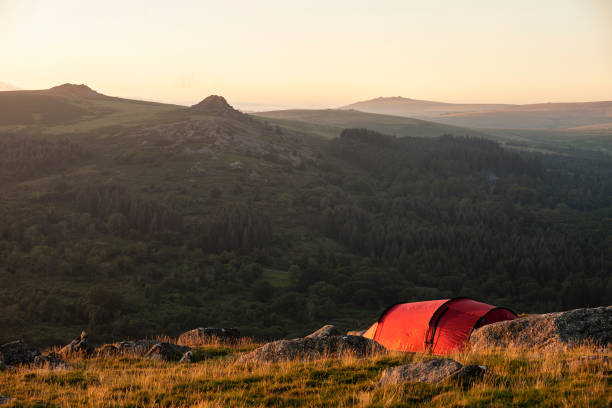 Stunning image of wild camping in English countryside during stunning Summer sunrise with warm glow of the sun lighting the landscape stock photo