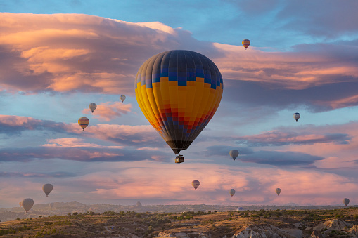 Stunning morning view and balloons in Cappadocia taking off at sunrise. Every day over 100 balloons fly taking tourist on a magical view of Nevsehir.